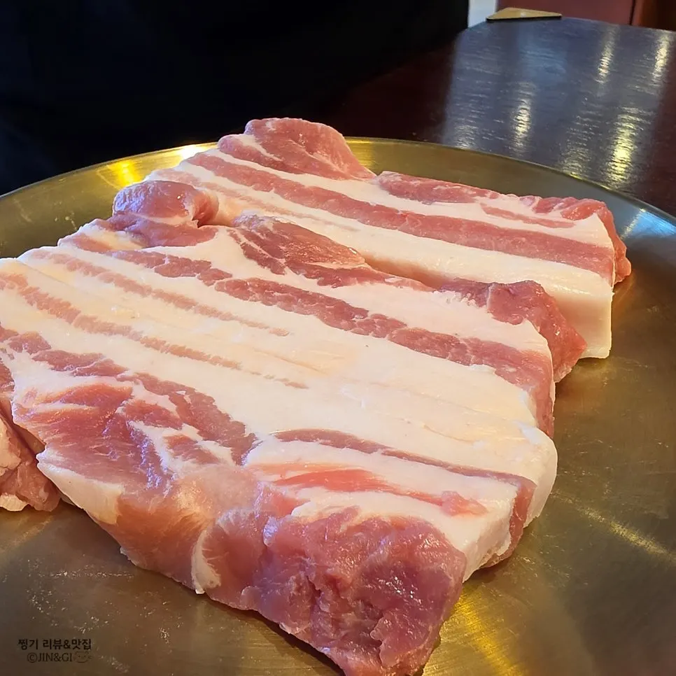 Fresh pork belly grilling over charcoal