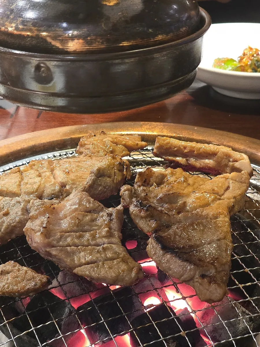 Marinated pork ribs and pork neck grilling over charcoal