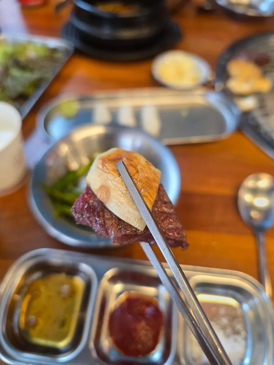 A piece of beef picked up with basic side dishes