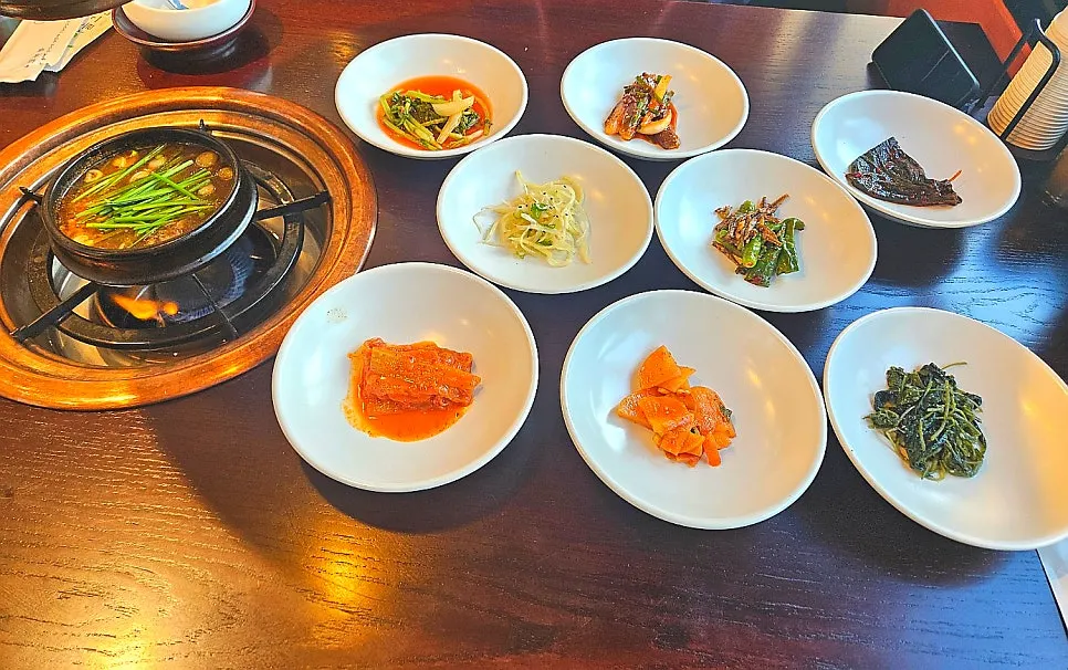 A spread of basic side dishes including kimchi, namul, and perilla leaf salad