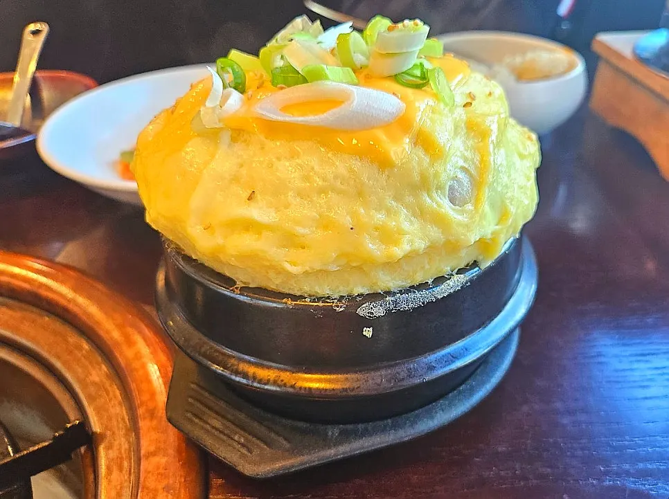 Egg custard in an earthenware pot topped with cheese and green onion
