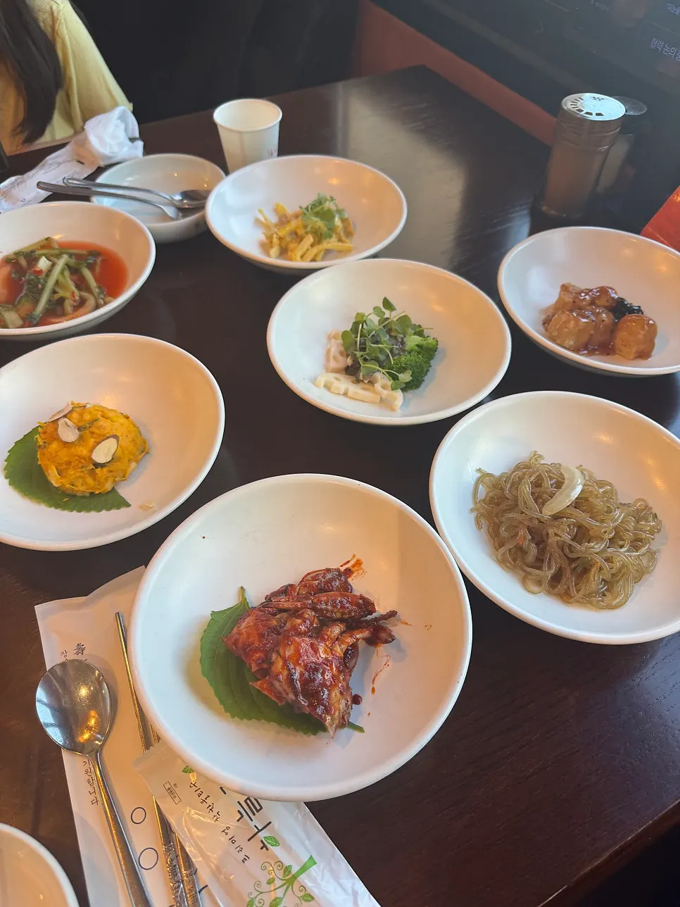 Full spread of basic side dishes including tofu tangsuyuk and japchae