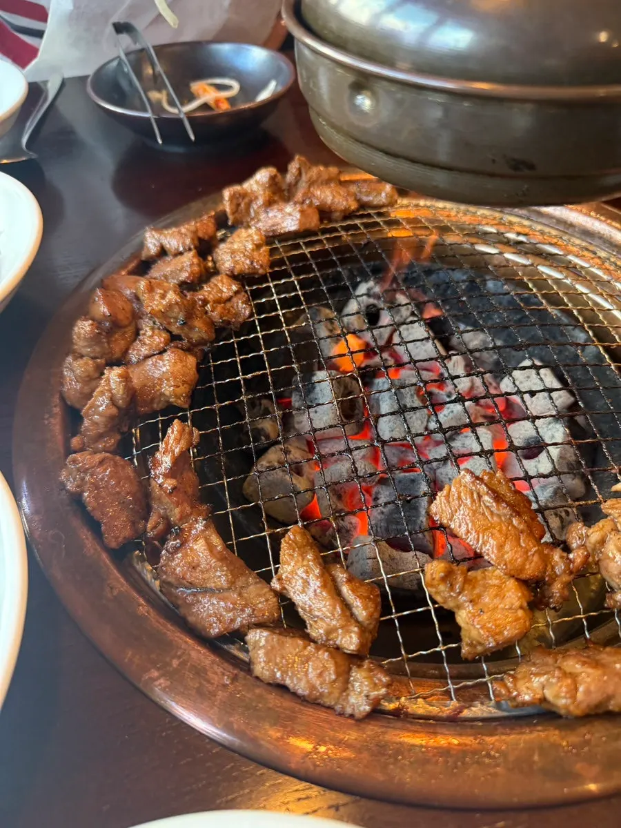 Grilled galbi moved to the side of the grill by the staff member