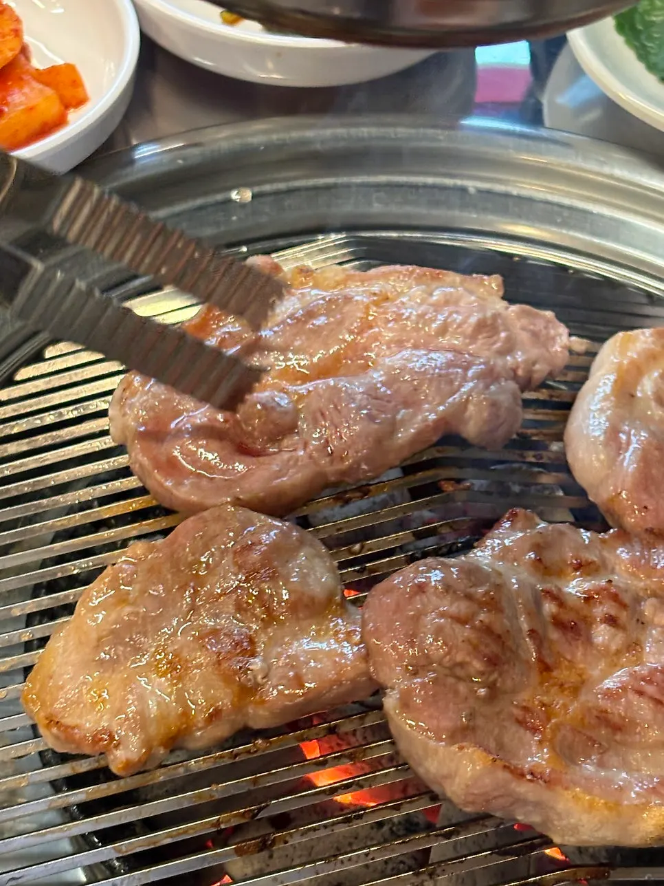 Charcoal-grilled pork neck browning nicely