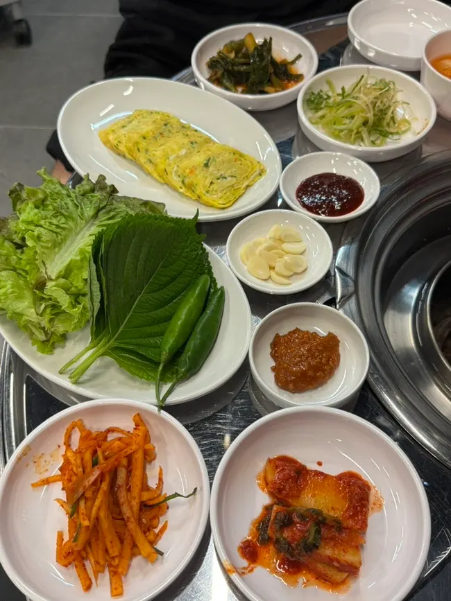Table spread with lettuce wraps, egg roll, kimchi, and shredded scallion