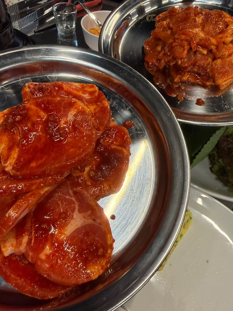 Table spread with ordered spicy raw pork belly and spicy meat patties