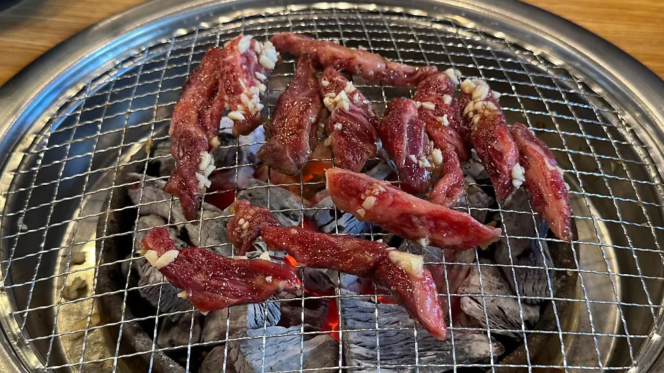 숯불 위에 올린 양념 소갈비살과 가니쉬