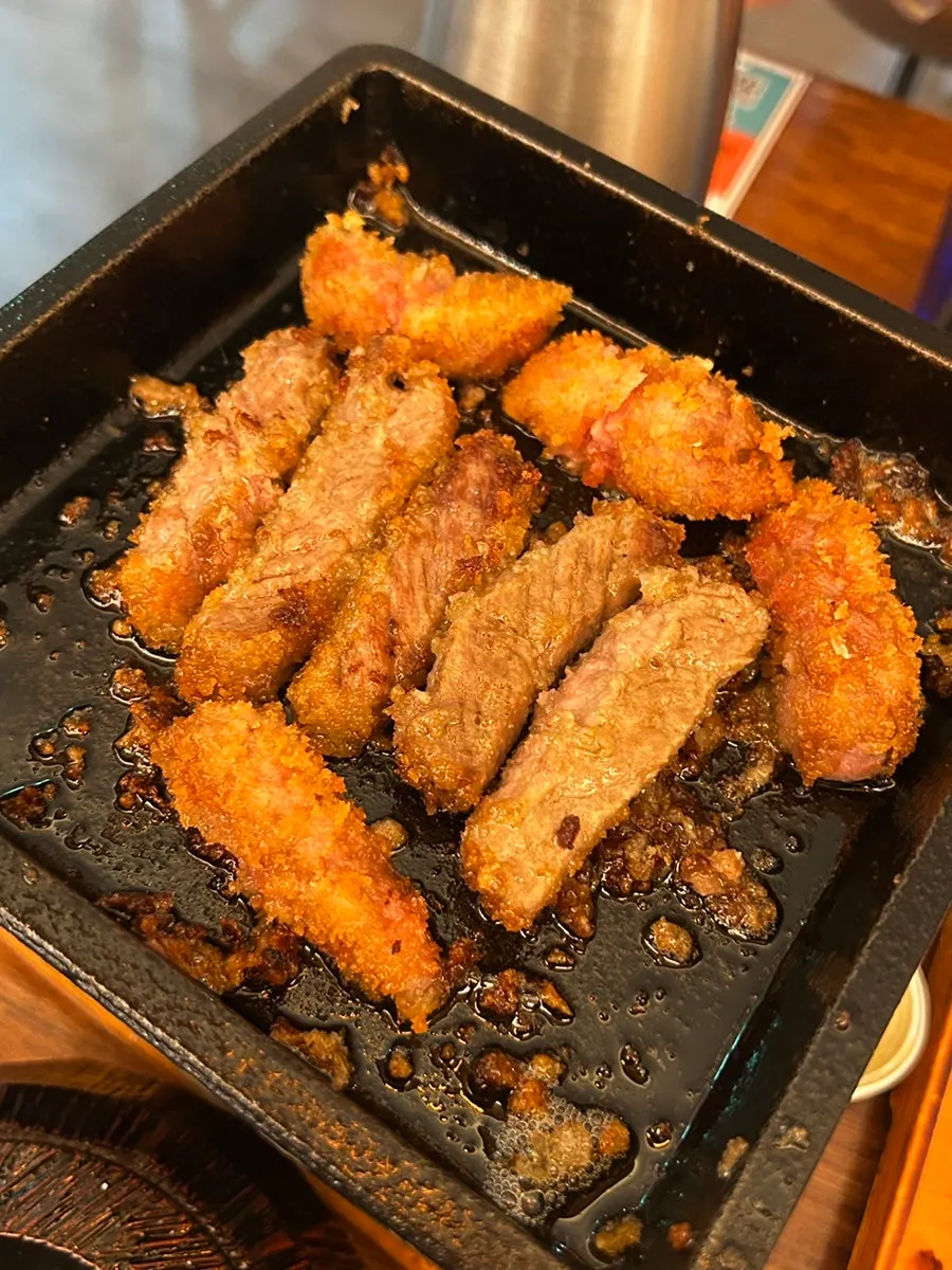 A bite of rice topped with gyukatsu and wasabi