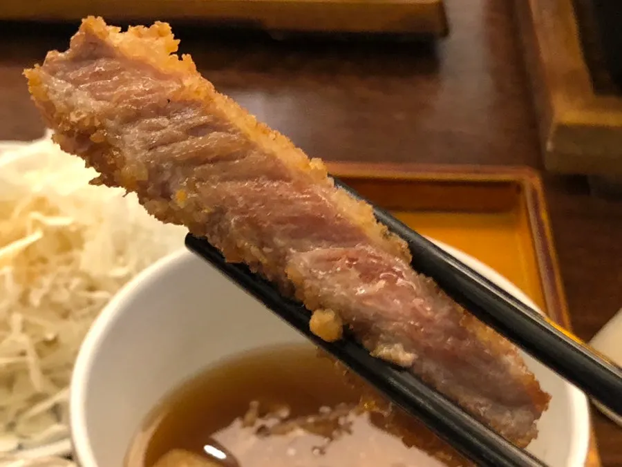 A piece of gyukatsu dipped in itame sauce