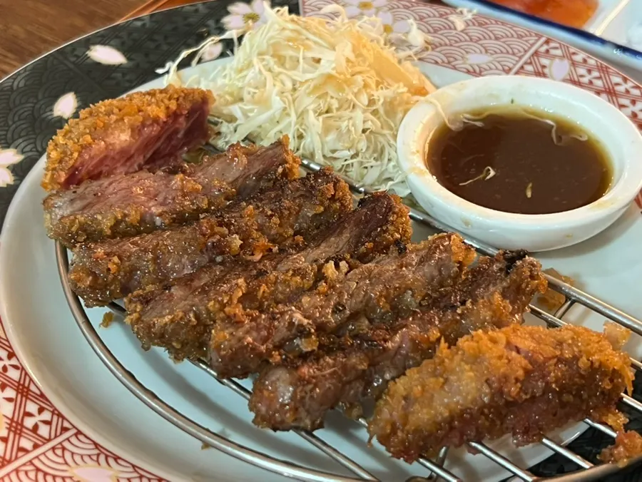 Several pieces of gyukatsu piled onto the grill at once