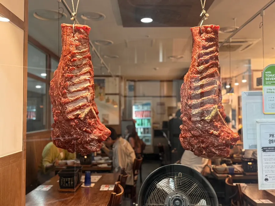 Whole cuts of meat hanging in front of the store
