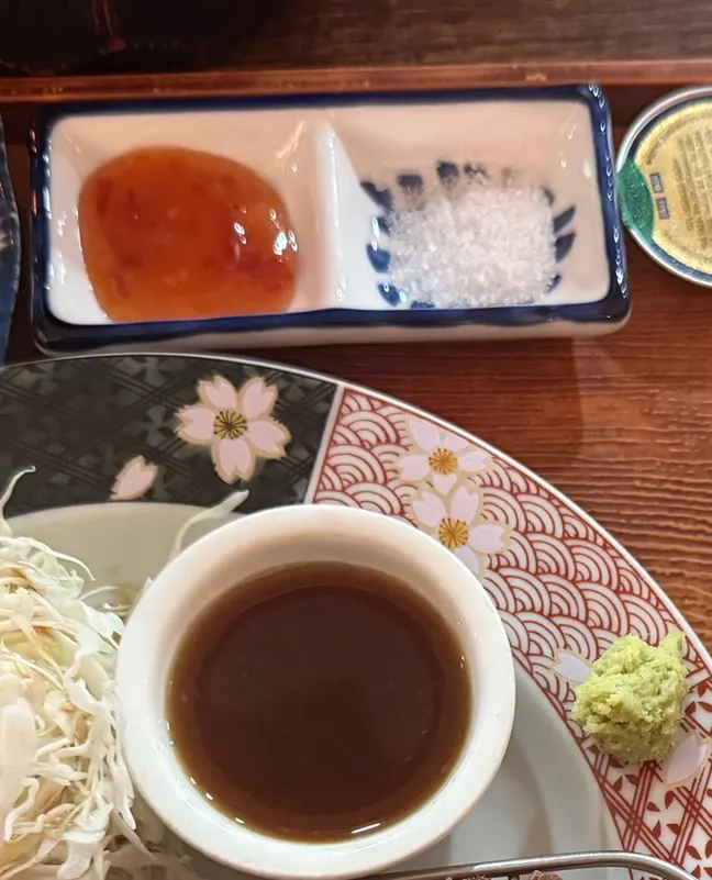 A plate with steak sauce, chili sauce, salt, and wasabi