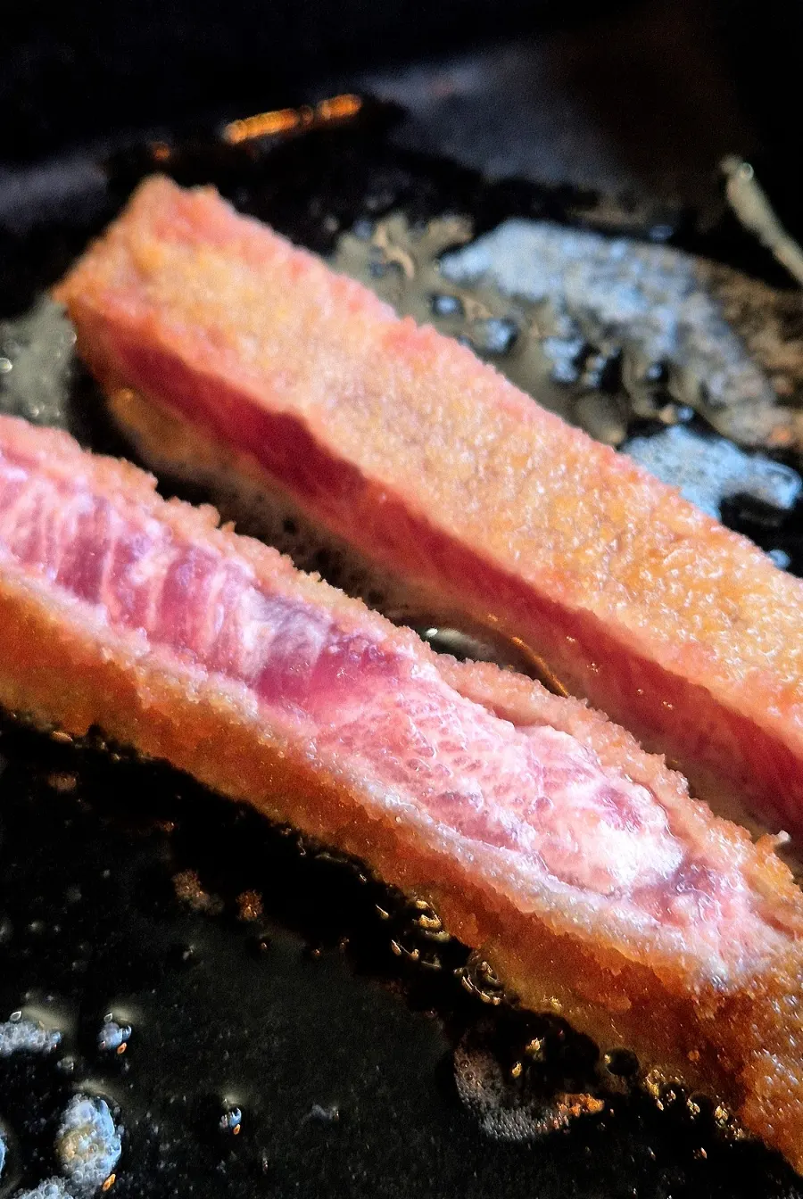 A piece of gyukatsu grilling on the tabletop grill