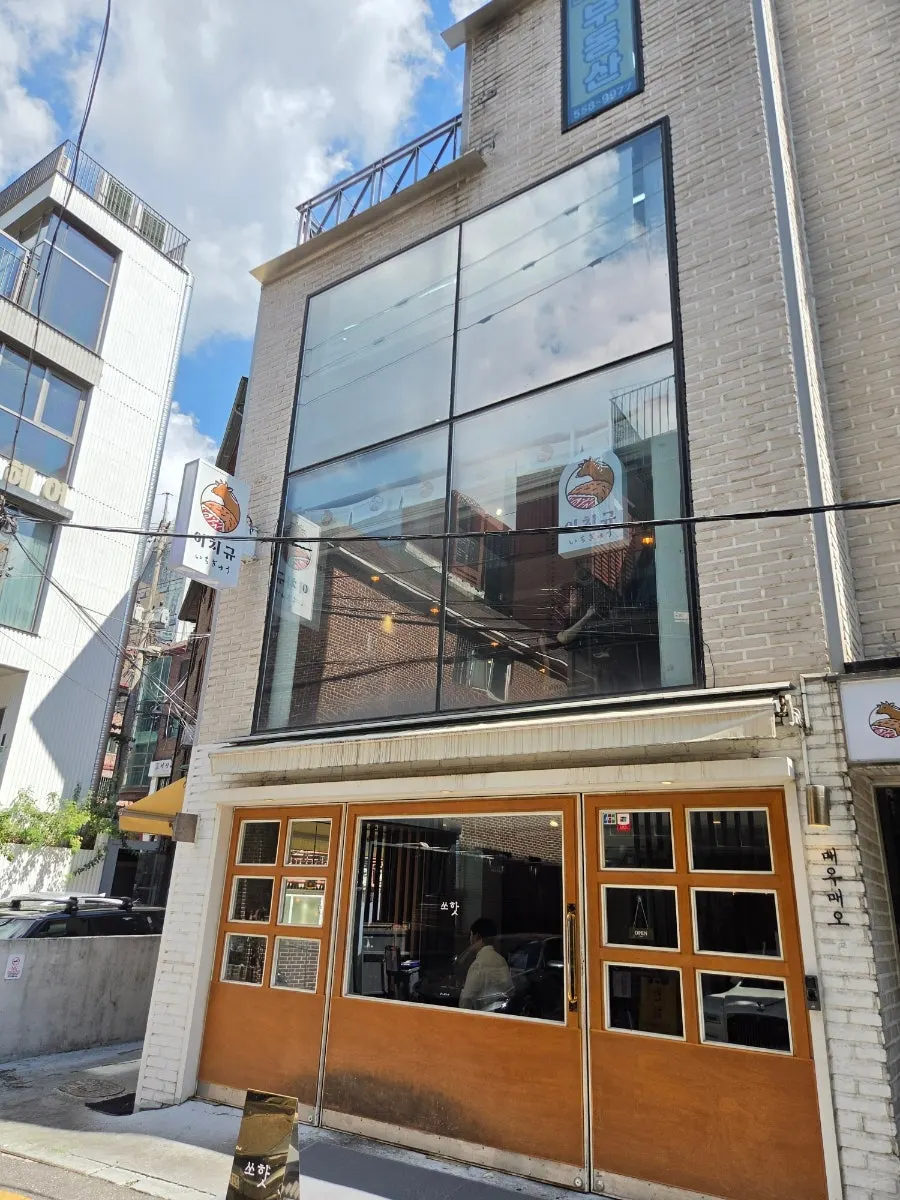 골목 안쪽 화이트 벽돌 건물의 이치규 강남신논현점 외관