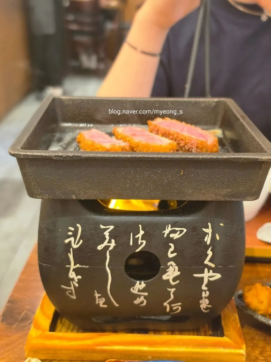 Piece of gyukatsu grilling on the buttered brazier