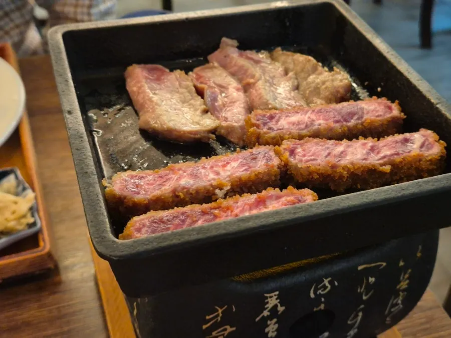 A piece of gyukatsu grilling on the mini brazier