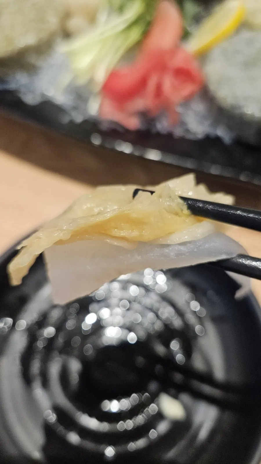 A piece of flounder dipped in wasabi soy sauce