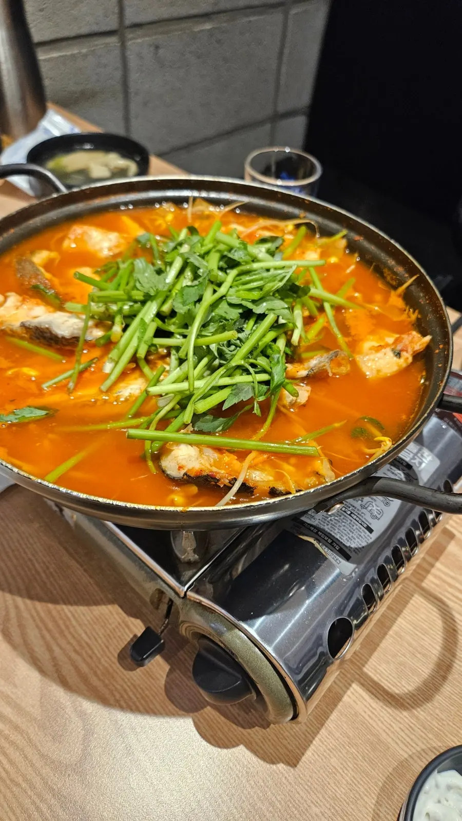 Pot of spicy fish stew topped with minari