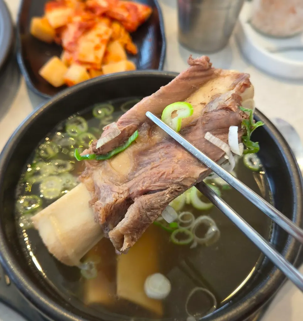 Clear galbitang broth topped with chopped green onion