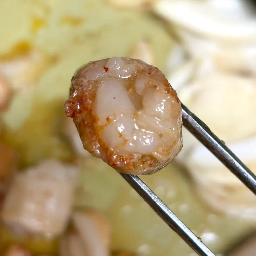 Seasoned grilled meat finishing over low heat while being turned