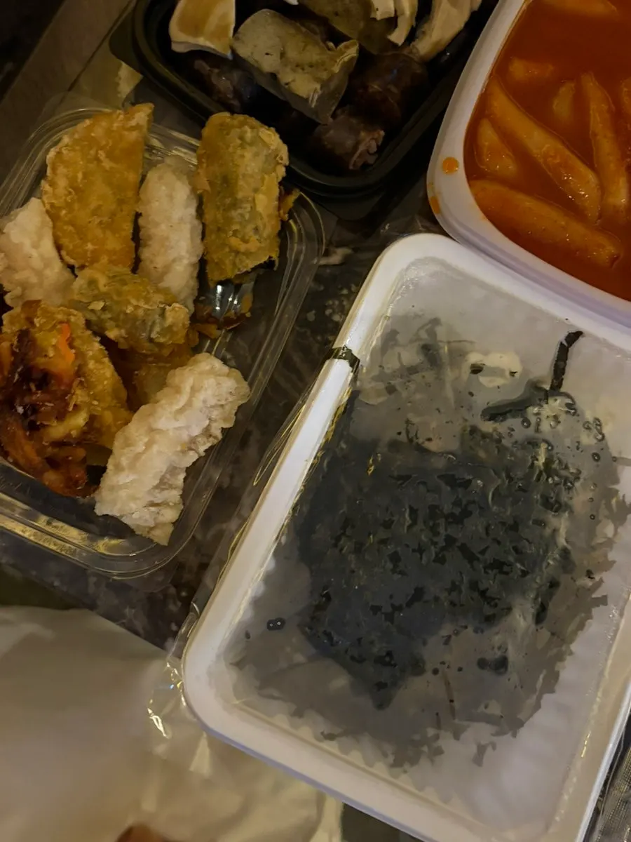 A piece of sundae dipped in tteokbokki sauce