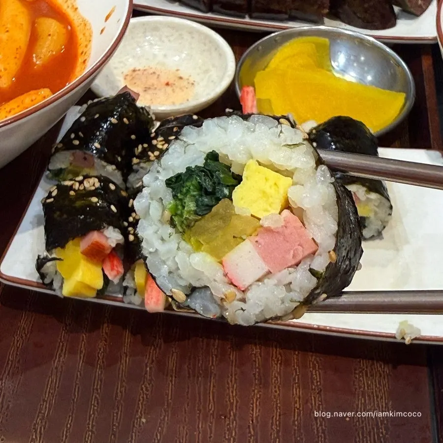 A piece of gimbap dipped into tteokbokki sauce