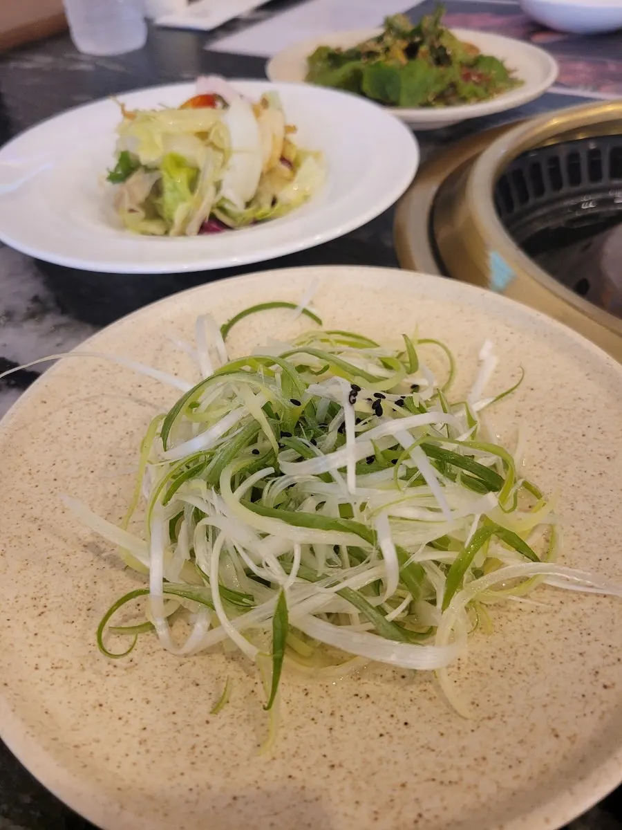 Three kinds of pickles — lotus root, onion, garlic scapes — with white kimchi