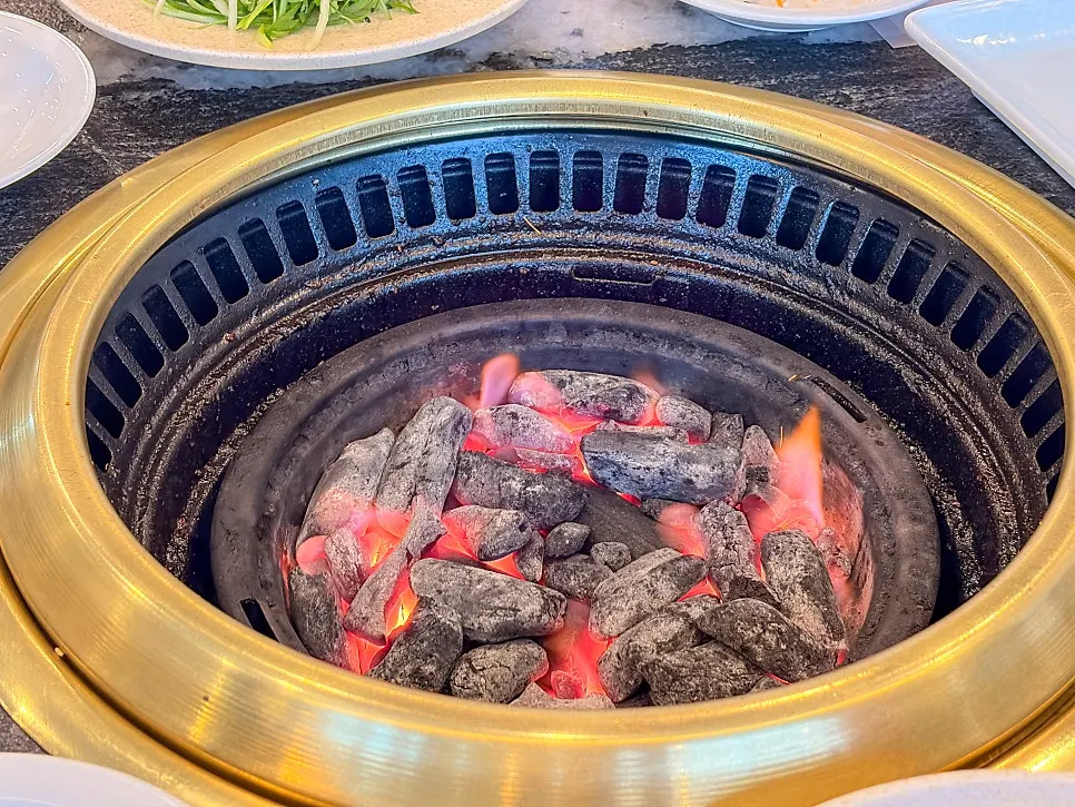 직원이 양념고기를 뒤집어 굽는 숯불 불판