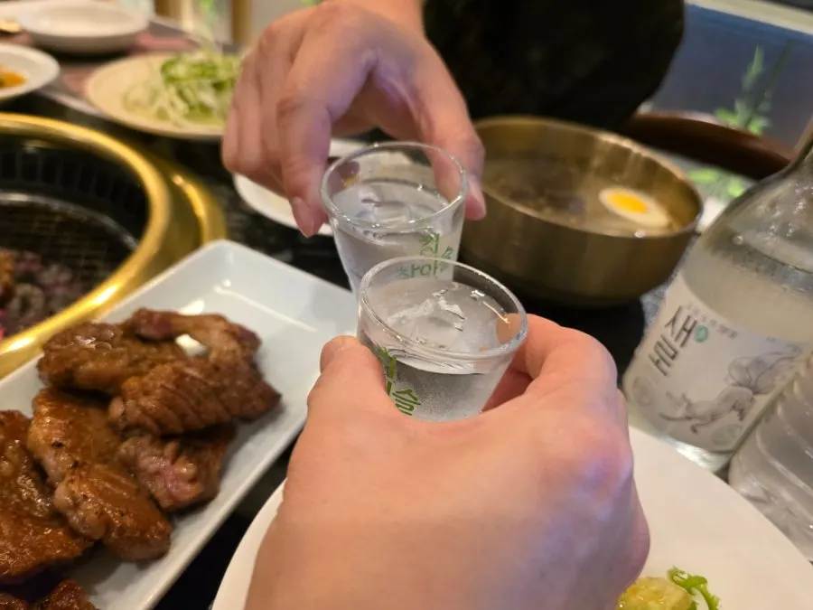 A glass of soju alongside pork galbi