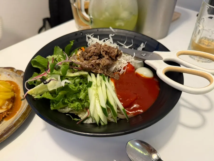 Stir-fried beef brisket jjolmyeon topped with brisket and vegetables