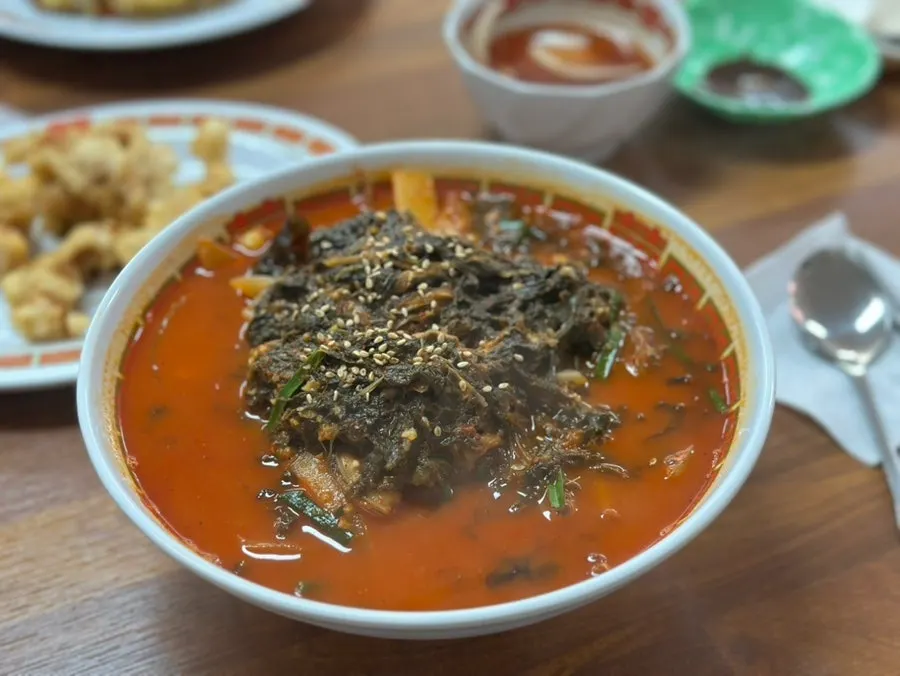 A bowl of seafood siraegi jjamppong piled high with dried radish greens