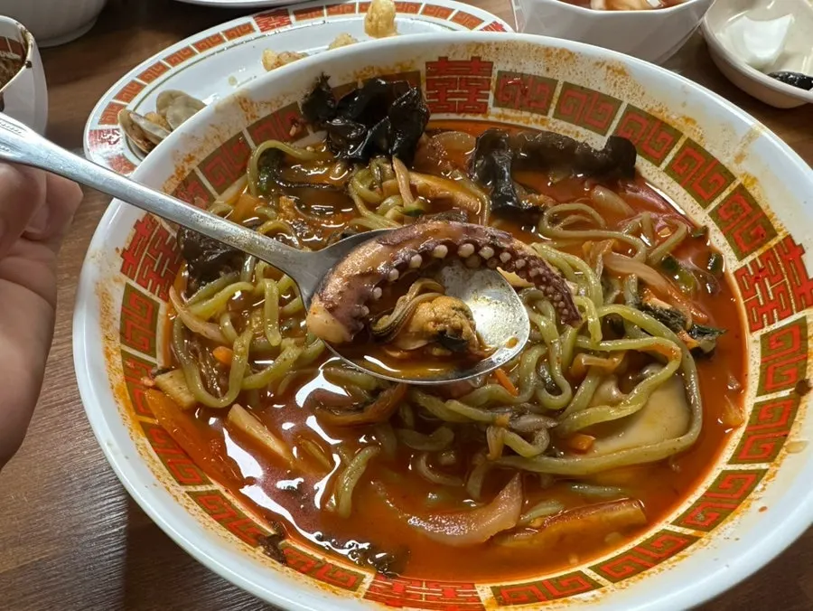 Chewy jjamppong noodles lifted up with chopsticks