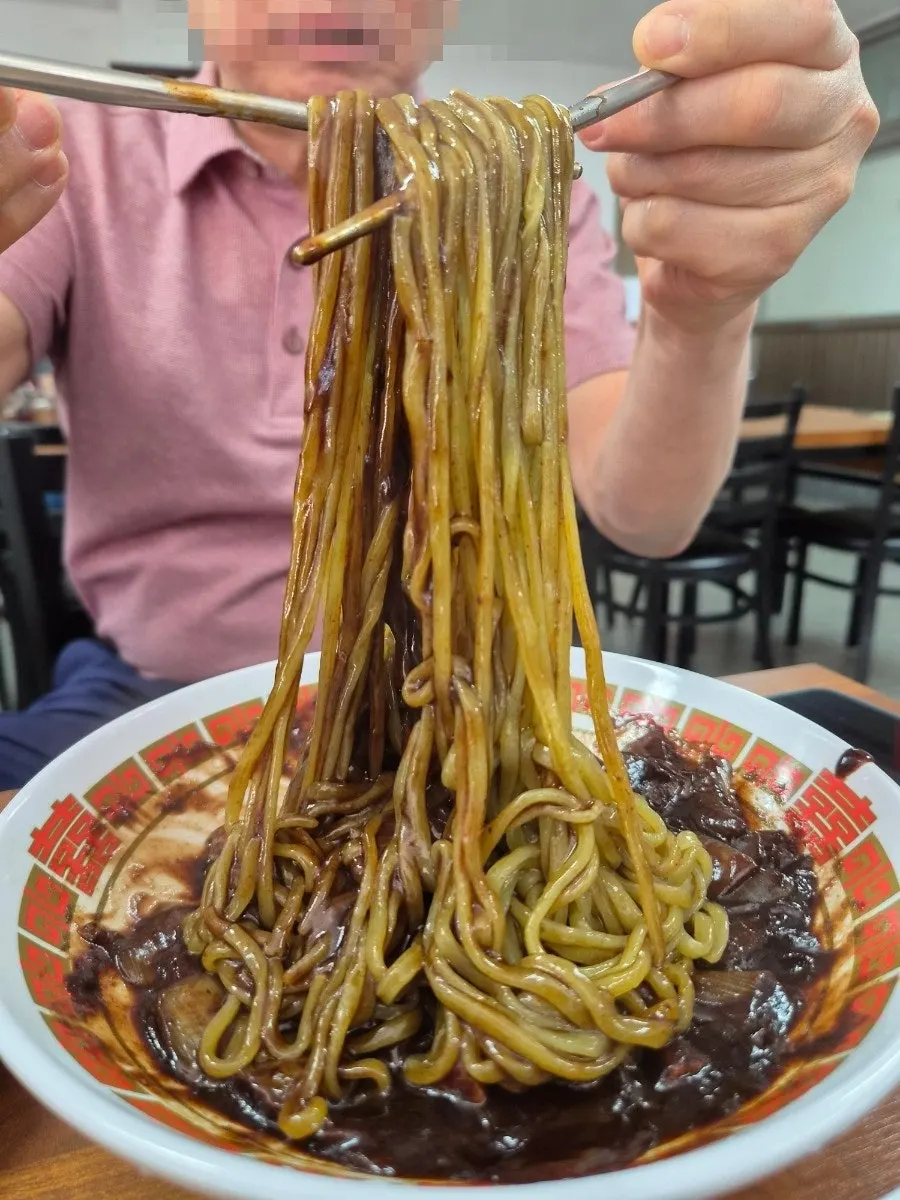 Chive noodles lifted up, mixed with jjajang sauce