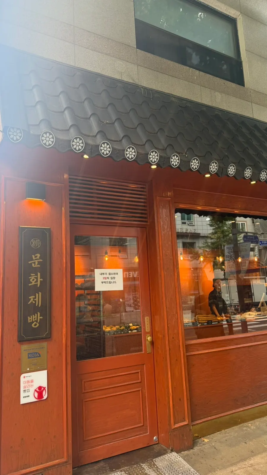 Sign showing Munhwa Bakery's hours with the storefront