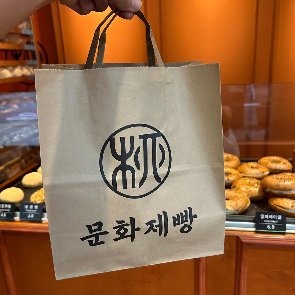 쇼핑백에 담긴 양파베이글과 빵 세 가지