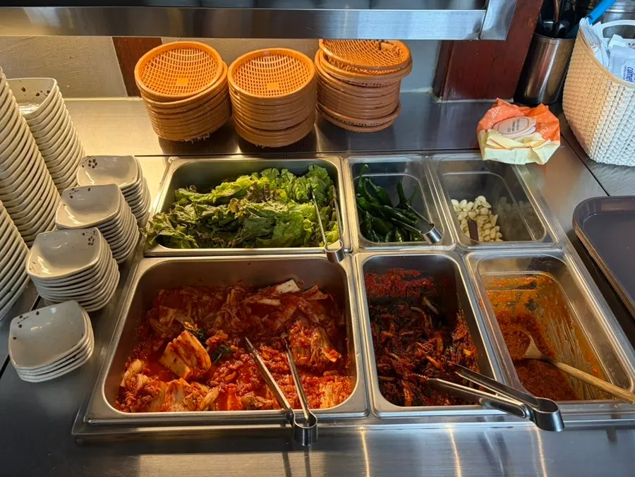 A plate of side dishes including green onion kimchi
