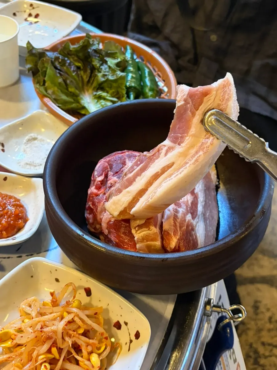 A plate of Meongseokjip's pork set next to the grill