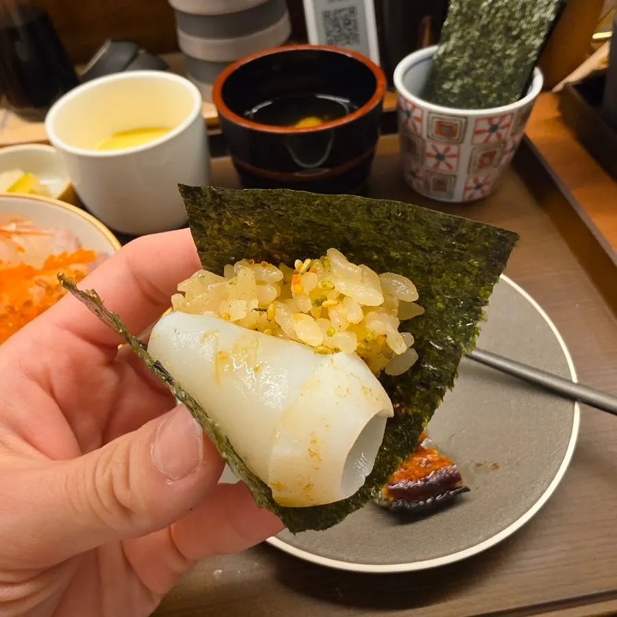 A bite of kaisendon sashimi wrapped in seaweed
