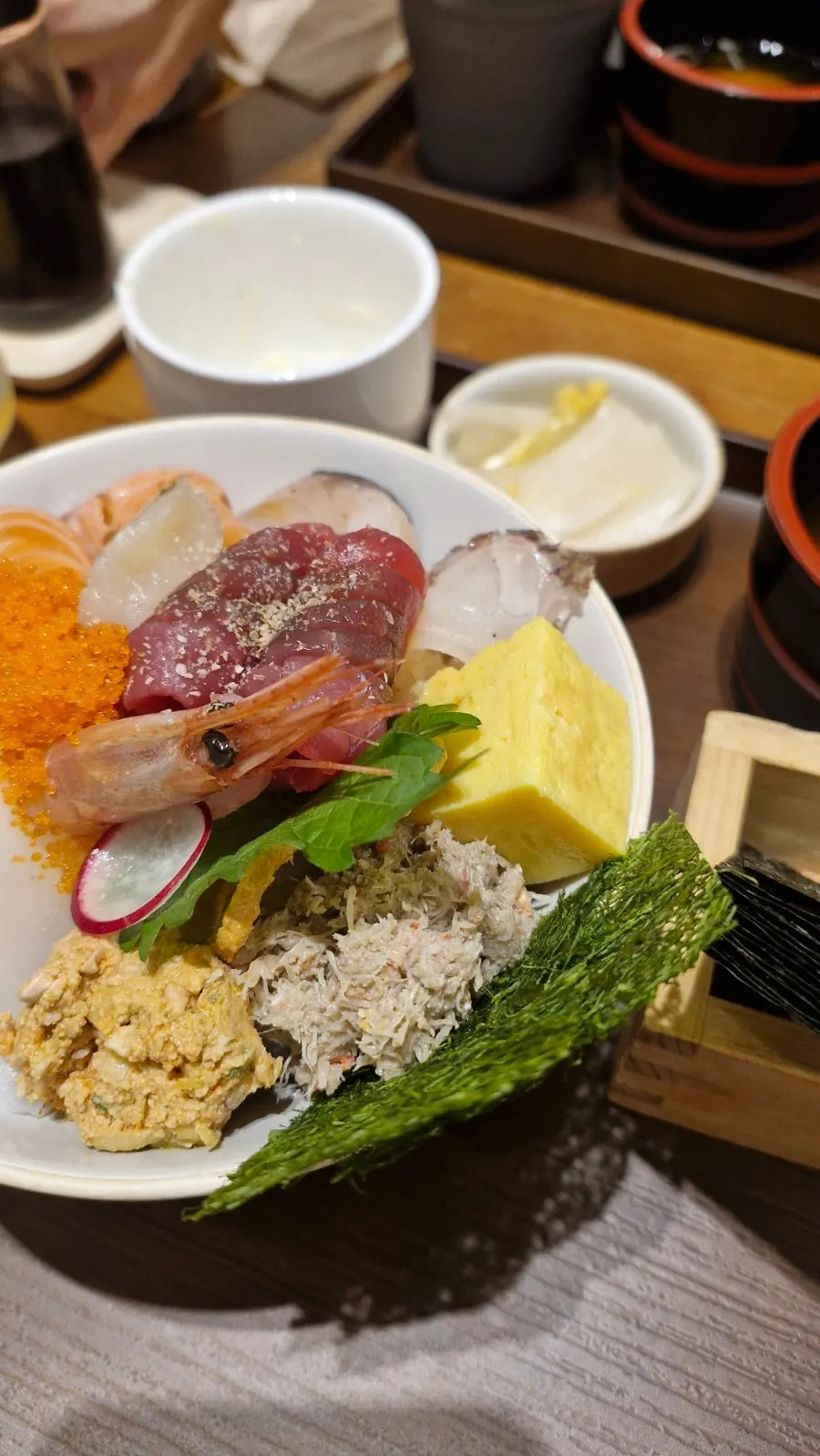 A bite of rice and sashimi wrapped in gamtae seaweed