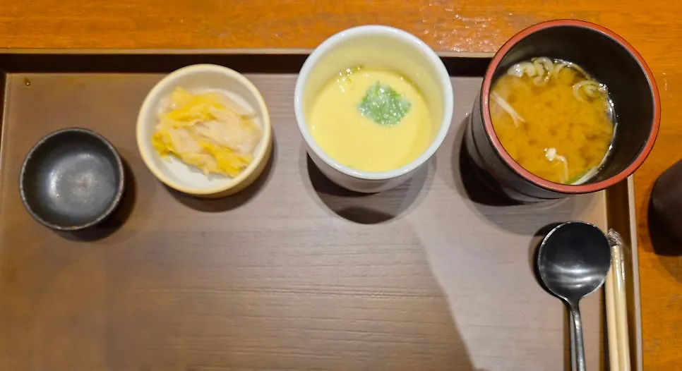 Table setting with steamed egg, broth, and kimchi served first