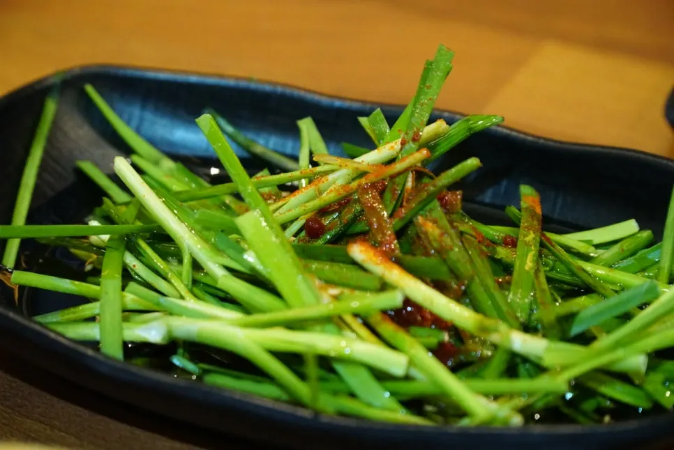 Plate of chive salad, pickled onion, and other basic side dishes