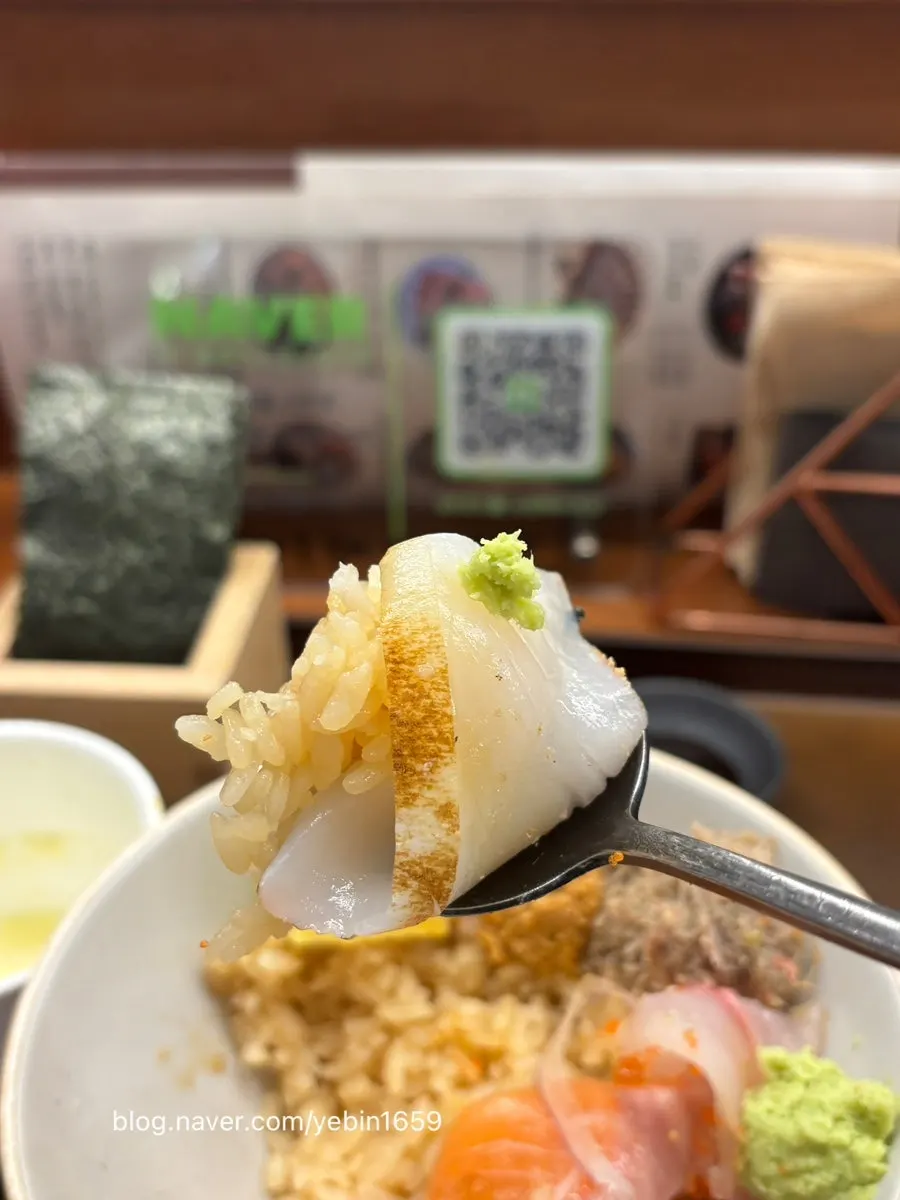 Picking up a piece of sashimi from the kaisendon