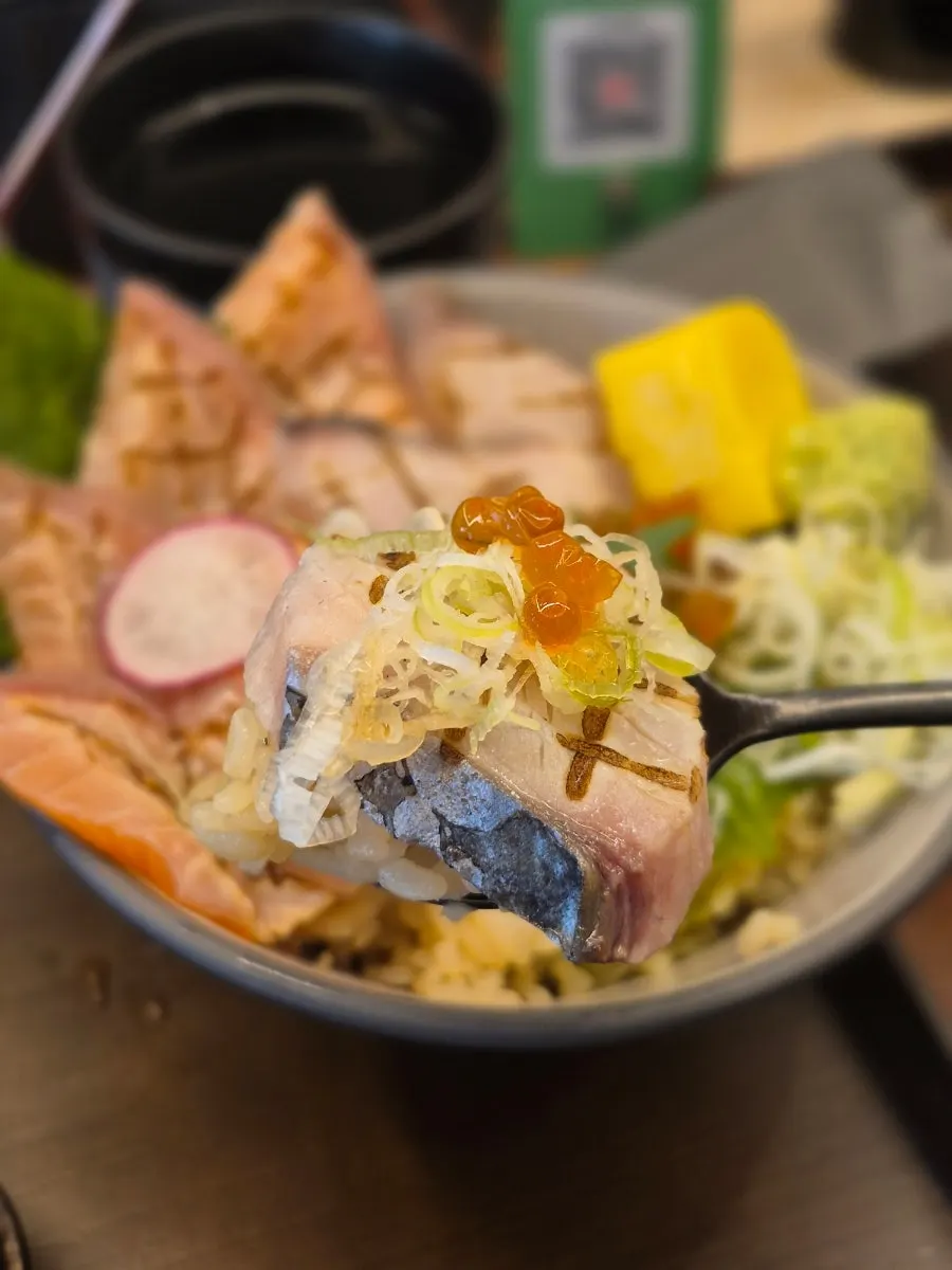 A spoonful of aburidon rice topped with mackerel and scallion