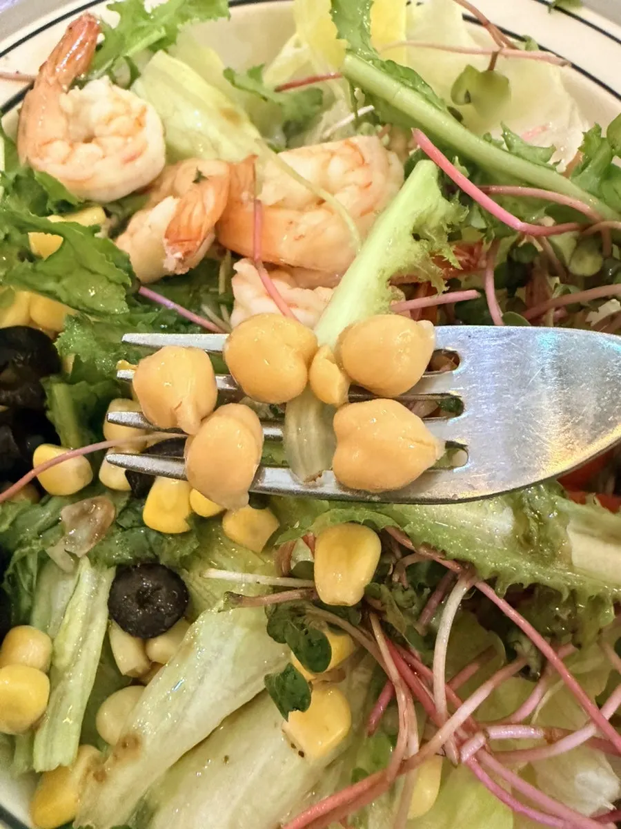 Salad topped with shrimp, corn, and tomato