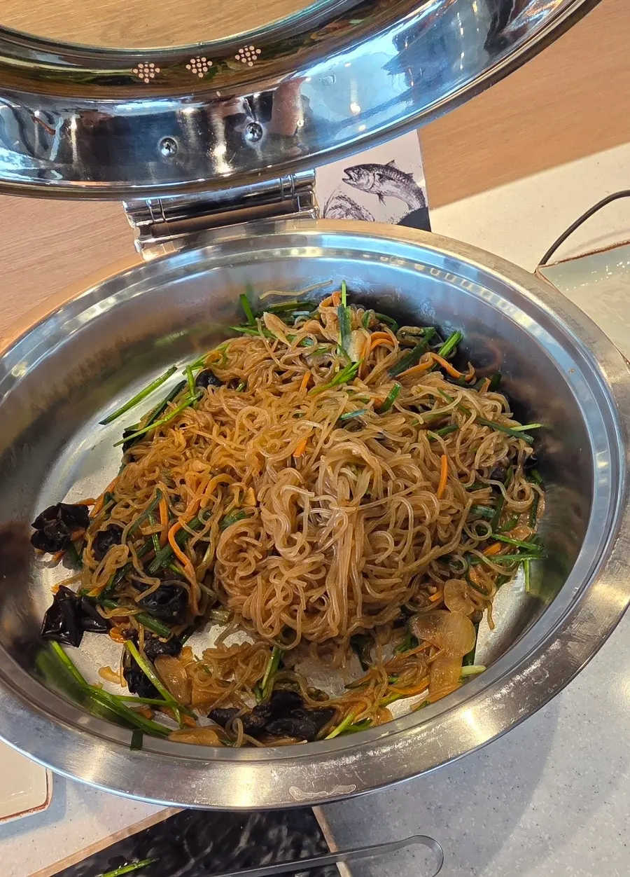 Plato con tteokbokki y japchae servidos desde la barra self-service