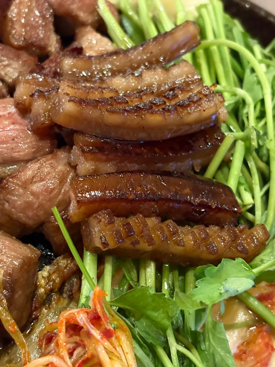 A piece of grilled pork belly picked up with chopsticks