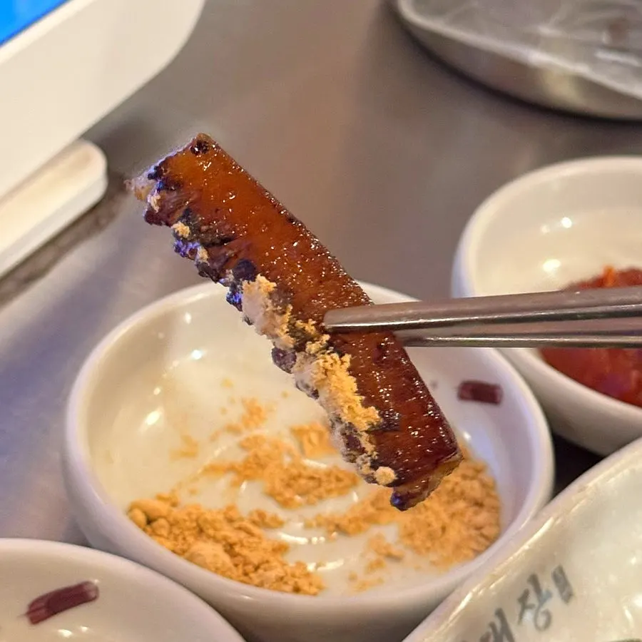 A bite of pork belly with kimchi on top