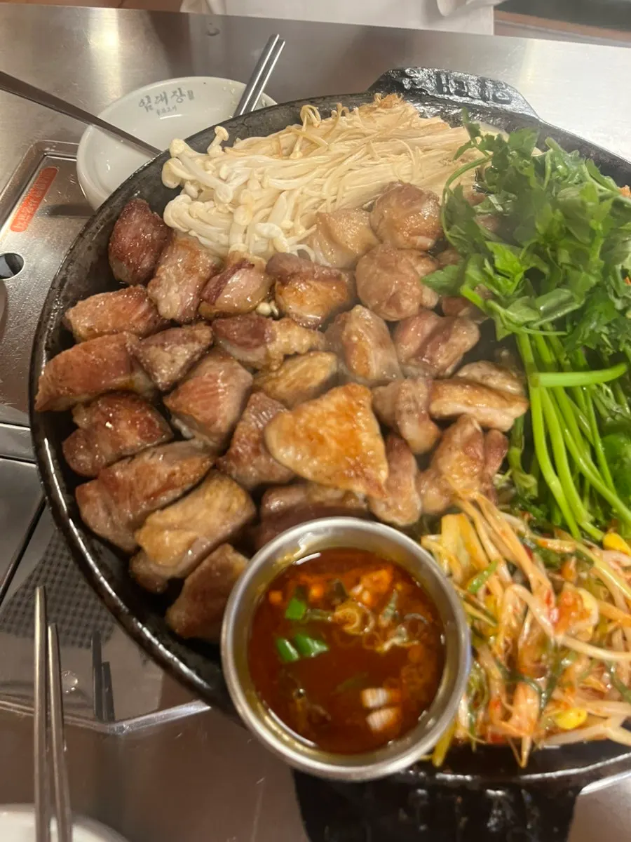 Grill plate topped with minari, kimchi, and enoki mushrooms