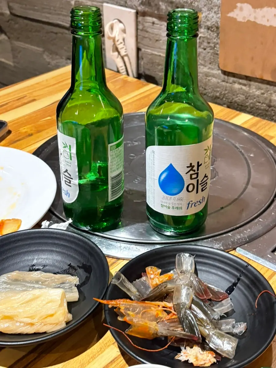 Bàn nhậu với sashimi tôm sống và chai rượu soju