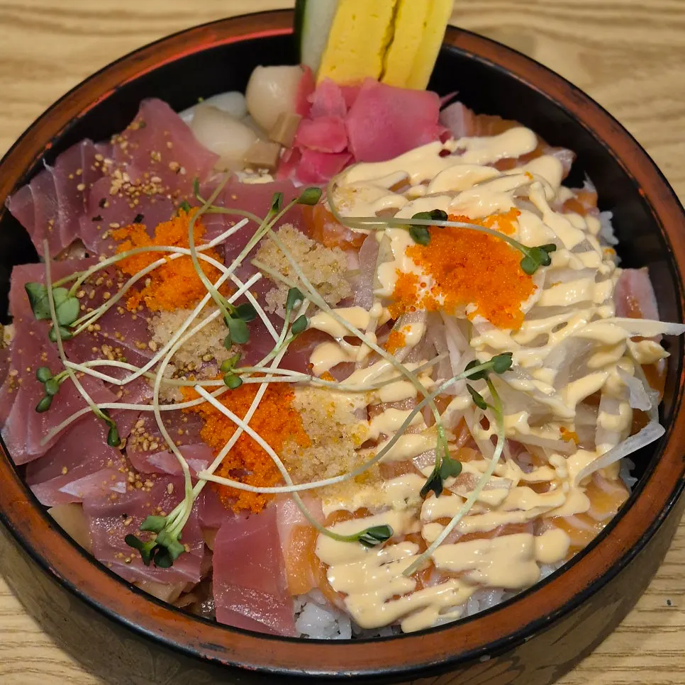 Salmon chirashi sushi topped with house sauce and flying fish roe